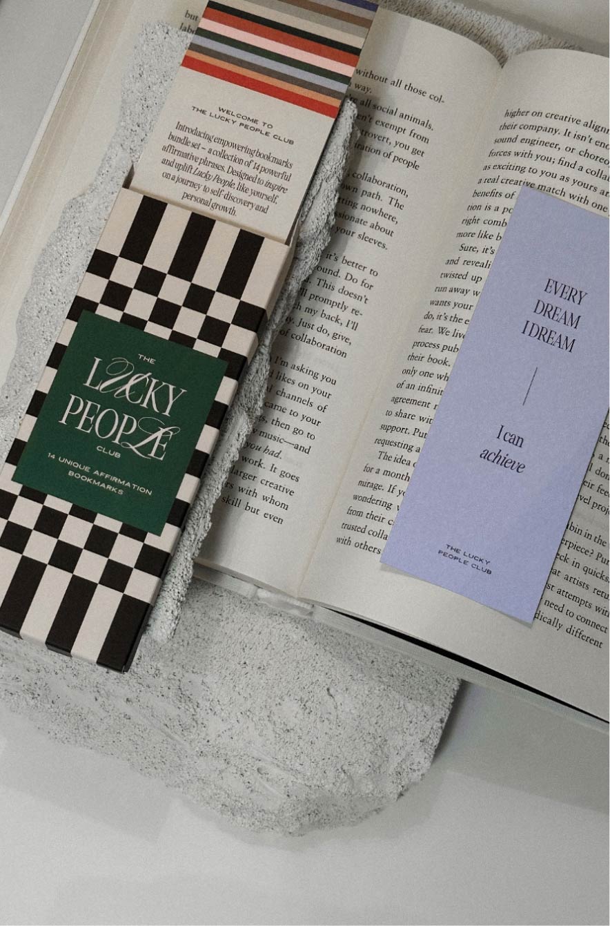 The Lucky People Club premium designer bookmarks and stationery resting on an open book.